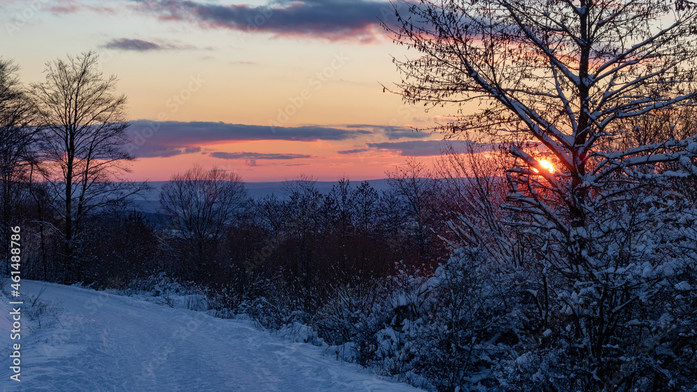 Sunset on a trail in the snowy mountains in winter near Riedenberg, Schwarze Berge, Rhoen, Germany.