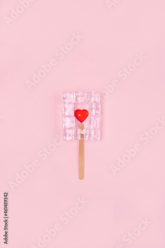 Ice cream with ice cubeas and red hearth in the middle on the pink background.Valentines day creative compostion. Minimal composition.