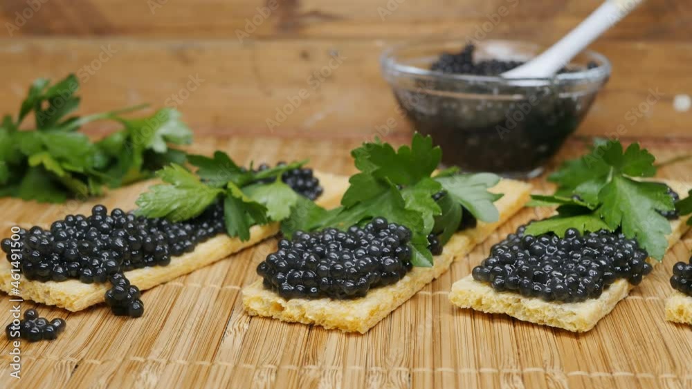 Close-up of black caviar sandwiches and crispy rectangular slices on a bamboo mat and wooden table. Dolly shot Close-up of black caviar sandwiches and crispy rectangular slices on a bamboo mat and wooden table. Dolly shot
