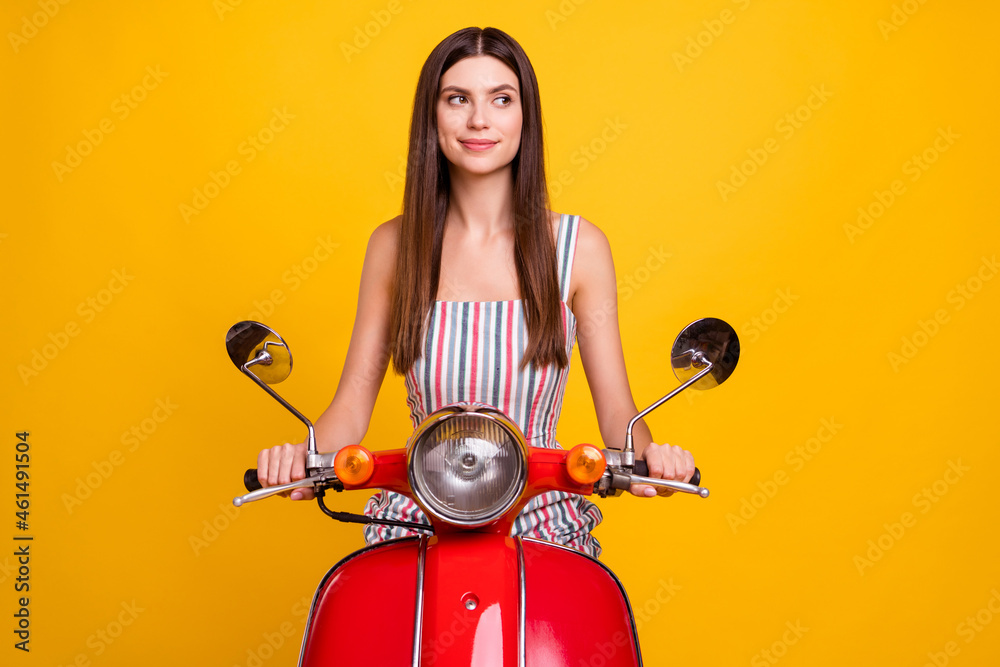 Photo portrait young woman driving bike in striped dress looking blank space isolated bright yellow color background