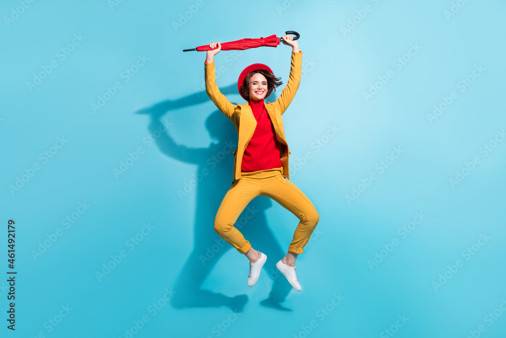Full length photo of young girl happy positive smile have fun jump fly parasol isolated over blue color background
