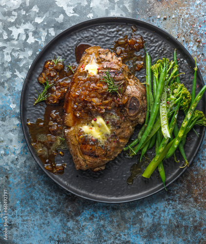 Pork Chop served with green vegetables on a black plate photo