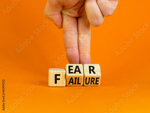 Fear of failure symbol. Businessman turns wooden cubes and changes the word 'failure' to 'fear'. Beautiful orange background, copy space. Business, fear of failure concept.