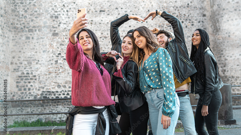 Group of young friends in the ancient city center taking a selfie with the smart phone - seven people have fun together