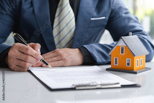 Man Signing A Contract When Buying A New House after agreeing to make a home purchase agreement and make a loan agreement. Discussion with a real estate agent ..