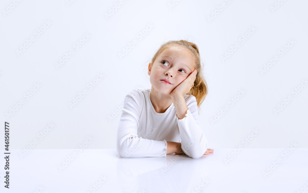 Portrait of beuatiful school girl sitting and looking at camera isolated on white background. Happy childhood, education Portrait of beuatiful school girl sitting and looking at camera isolated on white background. Happy childhood, education