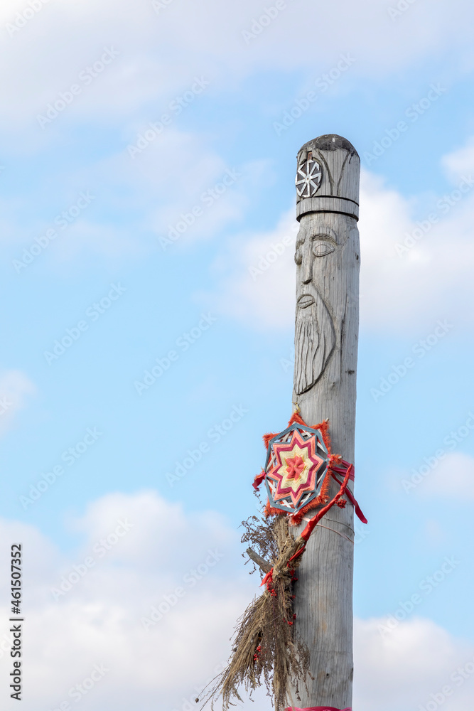Ancient wooden idol of the Slavic god against the sky. Slavic sun ...