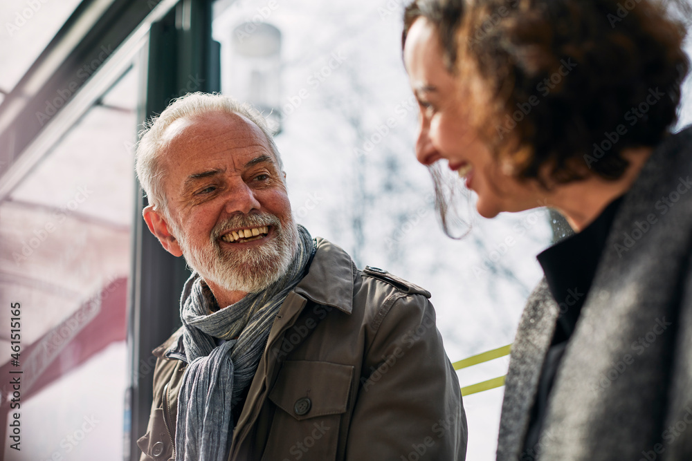 Smiling man talking to woman at bus stop Smiling man talking to woman at bus stop