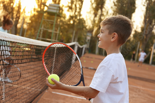 Cute little boy playing tennis on court outdoors © New Africa