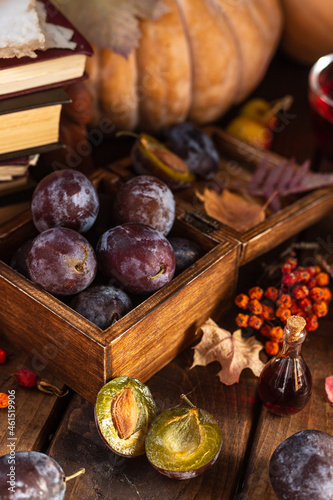 Plums in a wooden box. Two halves of a plum cut in half lie side by side.