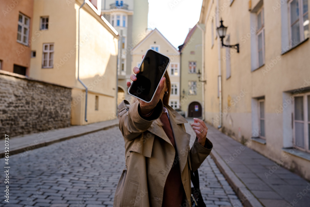 The girl shows a blank phone screen on the street. Close-up smartphone with copy space for text and informational content