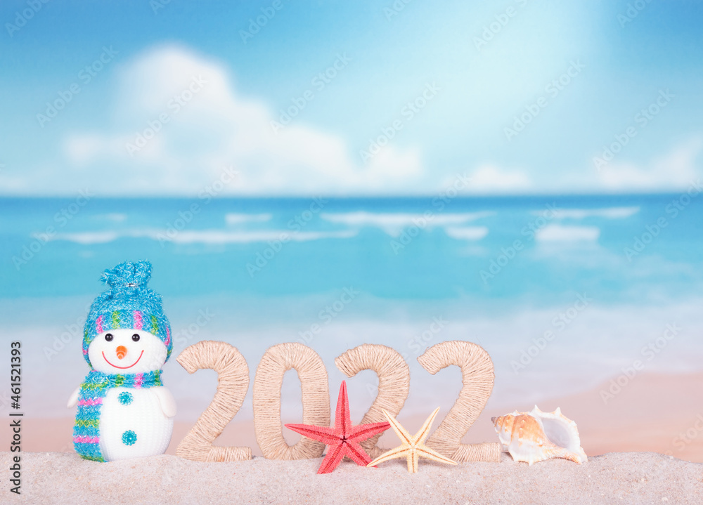 Fototapeta premium New year 2022 sign with snowman on beach background