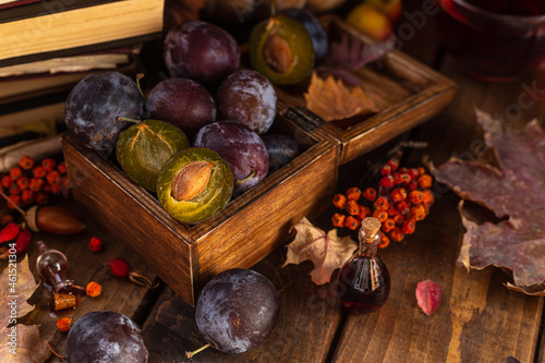 Plums in a wooden box. Two halves of a plum cut in half lie side by side.
