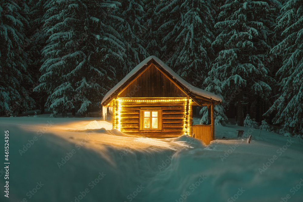 Fantastic winter landscape with glowing wooden cabin in snowy forest. Cozy house in Carpathian mountains. Christmas holiday concept - obrazy, fototapety, plakaty 