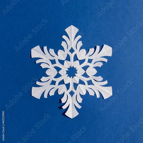 Handmade paper snowflake on blue background