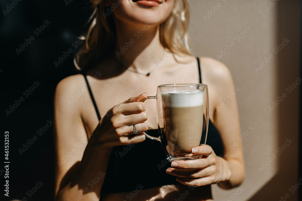 Closeup of a woman drinking coffee from a double glass cup, in sunlight. Closeup of a woman drinking coffee from a double glass cup, in sunlight.