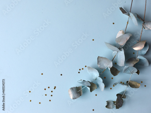 twig with blue and gold leaves on a blue pastel background, photo
