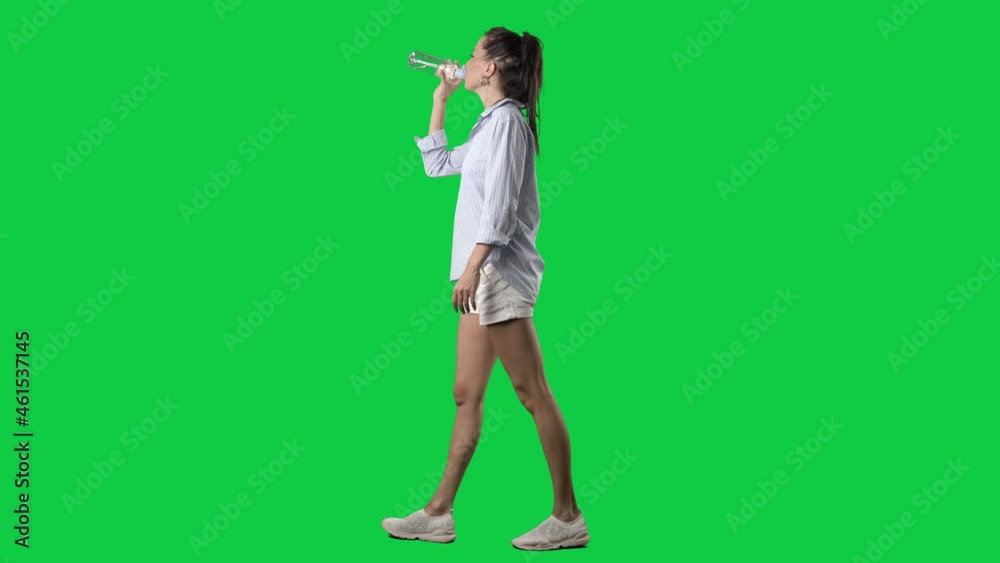 Side view of walking smart casual summer style woman drinking water from bottle. Full body on green screen chroma key background Side view of walking smart casual summer style woman drinking water from bottle. Full body on green screen chroma key background