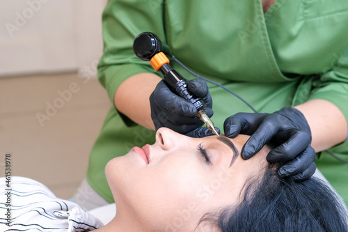 Beautician makes permanent eyebrow makeup on the face