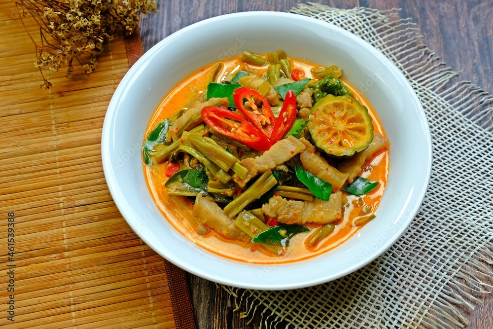 Authentic Thai red curry with pork belly and morning glory (Gaeng Tay Po) on wooden table. Thai food. Authentic Thai red curry with pork belly and morning glory (Gaeng Tay Po) on wooden table. Thai food.