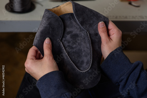 Shoemaker checking quality of the seam of handmade shoes in workshop. Female hands holding craft leather shoe.