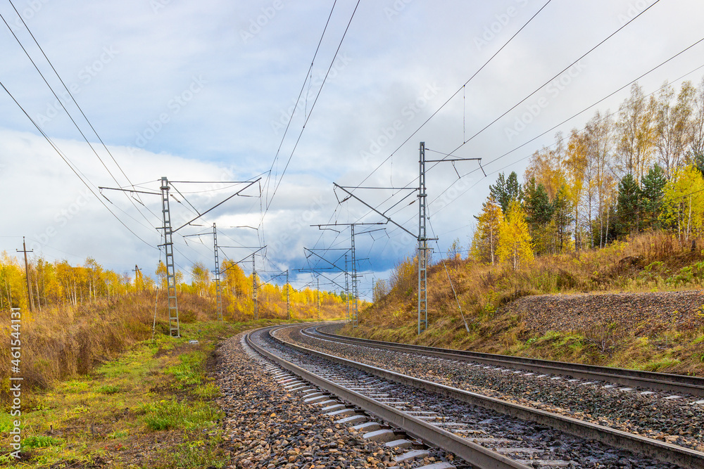 Golden autumn landscape on empty curved railroad in Siberia. Industrial landscape. Railroad tracks turn right. Electric poles with wires along the railway Golden autumn landscape on empty curved railroad in Siberia. Industrial landscape. Railroad tracks turn right. Electric poles with wires along the railway
