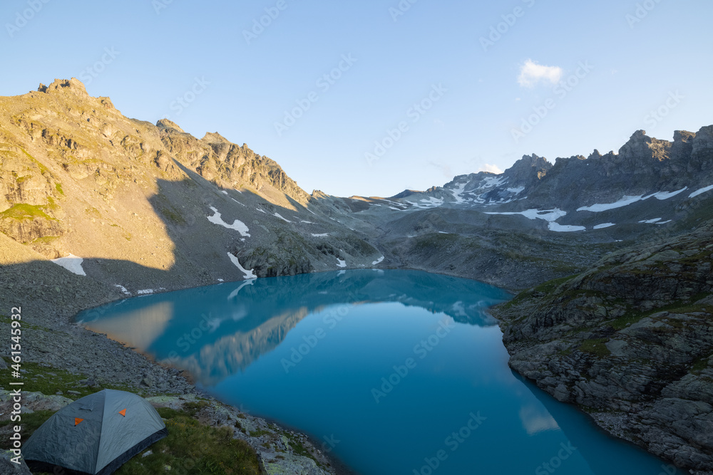 Wonderful scenery at an alpine lake called Wildsee in the canton of Saint Gallen. Epic sunset in the alps of Switzerland. Beautiful view with the tent in front and a perfect camping day.