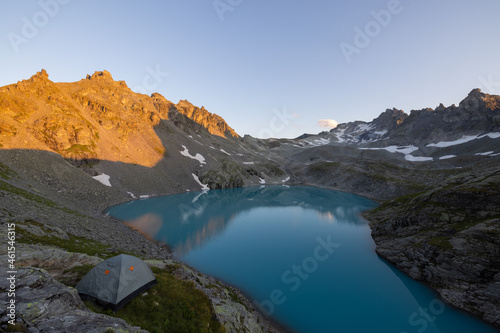 Wonderful scenery at an alpine lake called Wildsee in the canton of Saint Gallen. Epic sunset in the alps of Switzerland. Beautiful view with the tent in front and a perfect camping day.
