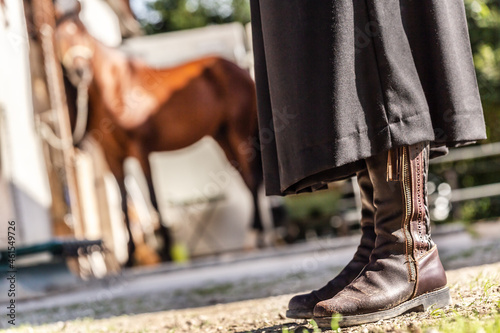 Classic equestrian art: A rider in jackboots in front of a tied P.R.E. horse at a horse barn