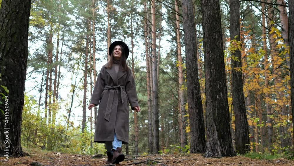 Attractive woman in coat and hat walking in the park in autumn on a sunny day and smiling. Attractive woman in coat and hat walking in the park in autumn on a sunny day and smiling.