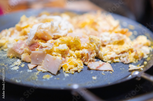 Scrambled eggs with chopped turkey ham on a round griddle