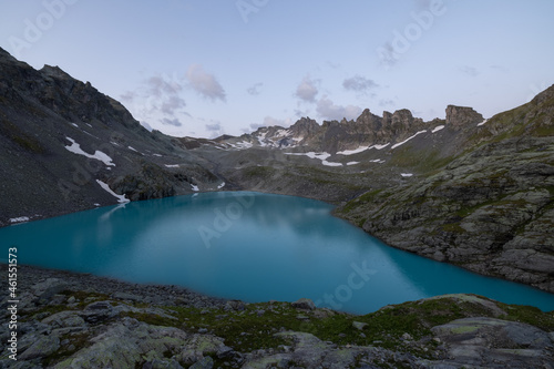 Wonderful morning view over an beautiful alpine lake called Wildsee in Switzerland. Amazing clear blue lake and the sun shine to the peaks of the glacier.