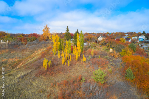 Summer houses between trees with red and yellow foliage. Autumn. Shooting from a drone.