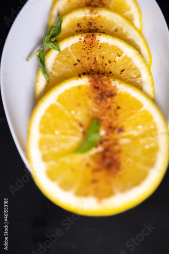 Plate of orange slices with chili powder on black surface