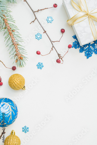 Flat lay frame with christmas balls, fir branches, snowflakes and gift box on a white background. Merry christmas card and copy space for your text