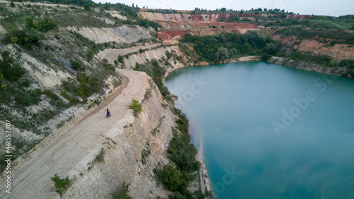 A motorbike driving near a cliff above a lake, Aerial drone shot photo