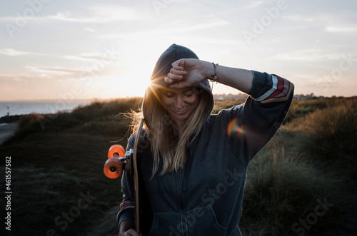 woman holding her skateboard at sunset at the beach photo