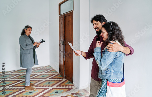 Happy Diverse Couple Examining Apartment Scheme With Realtor photo