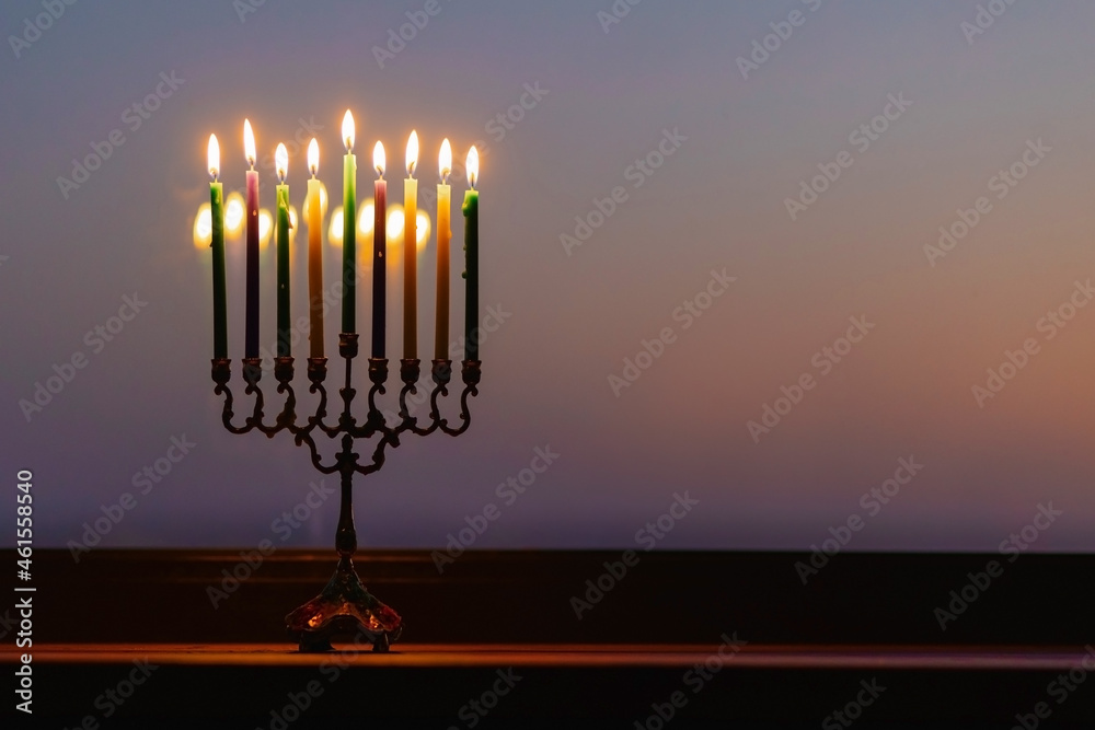 lights the menorah for Hanukkah at sunset sky. Jewish holiday