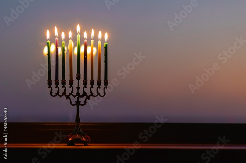 lights the menorah for Hanukkah at sunset sky.  Jewish holiday. Tradition is a religion ritual. The first star. Judaism. background banner. burning candle 