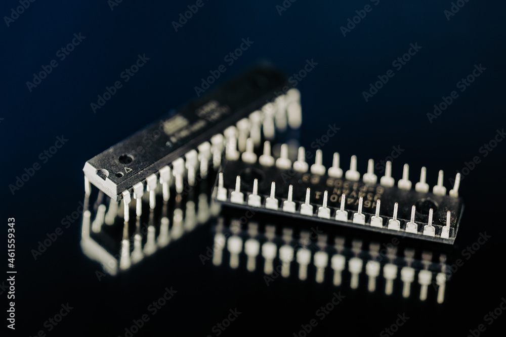 DIP microchips electronic components on dark blue mirror macro shot. DIP microchips electronic components on dark blue mirror macro shot.