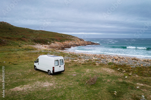 Drone aerial view of a camper van on a wild beach with green landscape in Galicia, Spain photo