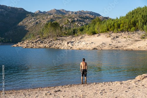 Caucasian man on a lake with mountains on the background in Vilarinho das Furnas Dam in Geres National Park, in Portugal photo