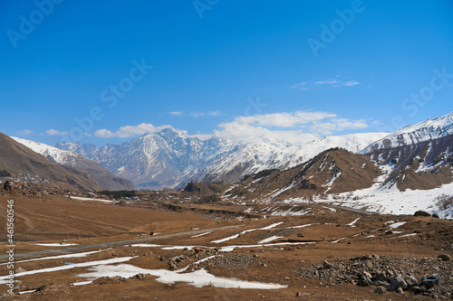 In a mountain valley, a breathtaking landscape of giant covered mountains in the background