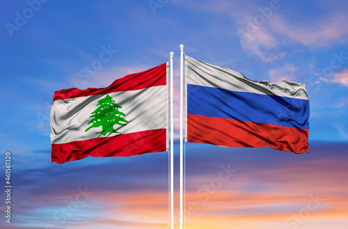 Russia and Lebanon two flags on flagpoles and blue cloudy sky