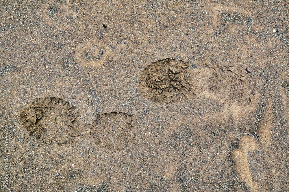 Footprints of men's shoes on the wet sand close-up.