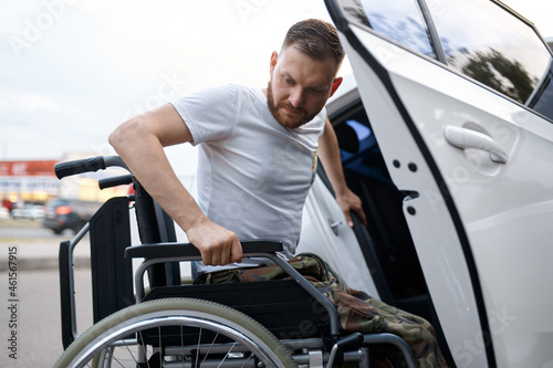 Bild auf Leinwand Retired veteran transfers from car to wheelchair