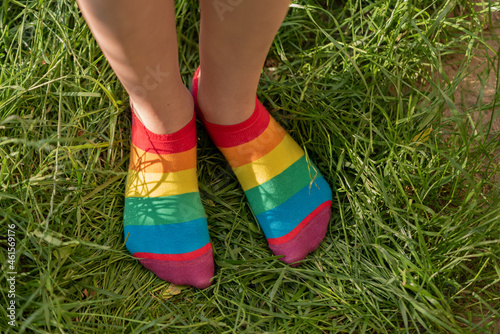 Rainbow socks on the girl's feet. Child's feet in colorful socks on the green grass.