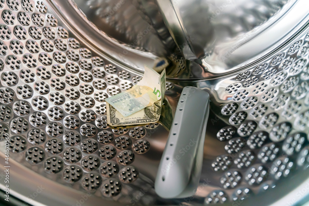 ..Dollars and euros in cash are washed in the drum of a washing machine. Banknotes are inside the washing machine. The concept of non-legal money laundering..