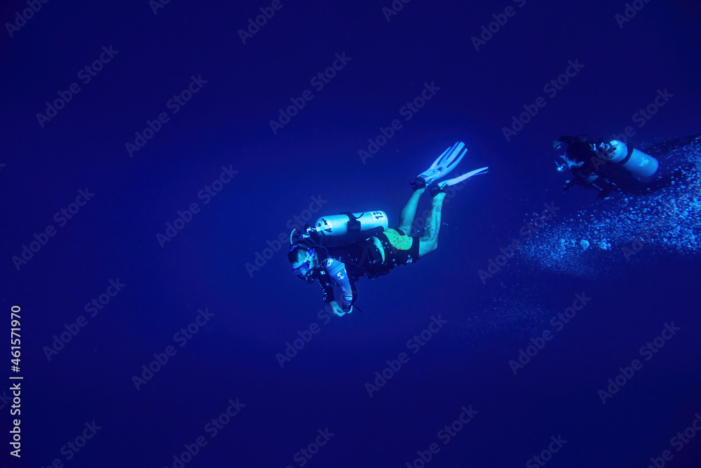 Two scuba divers swimming in deep blue